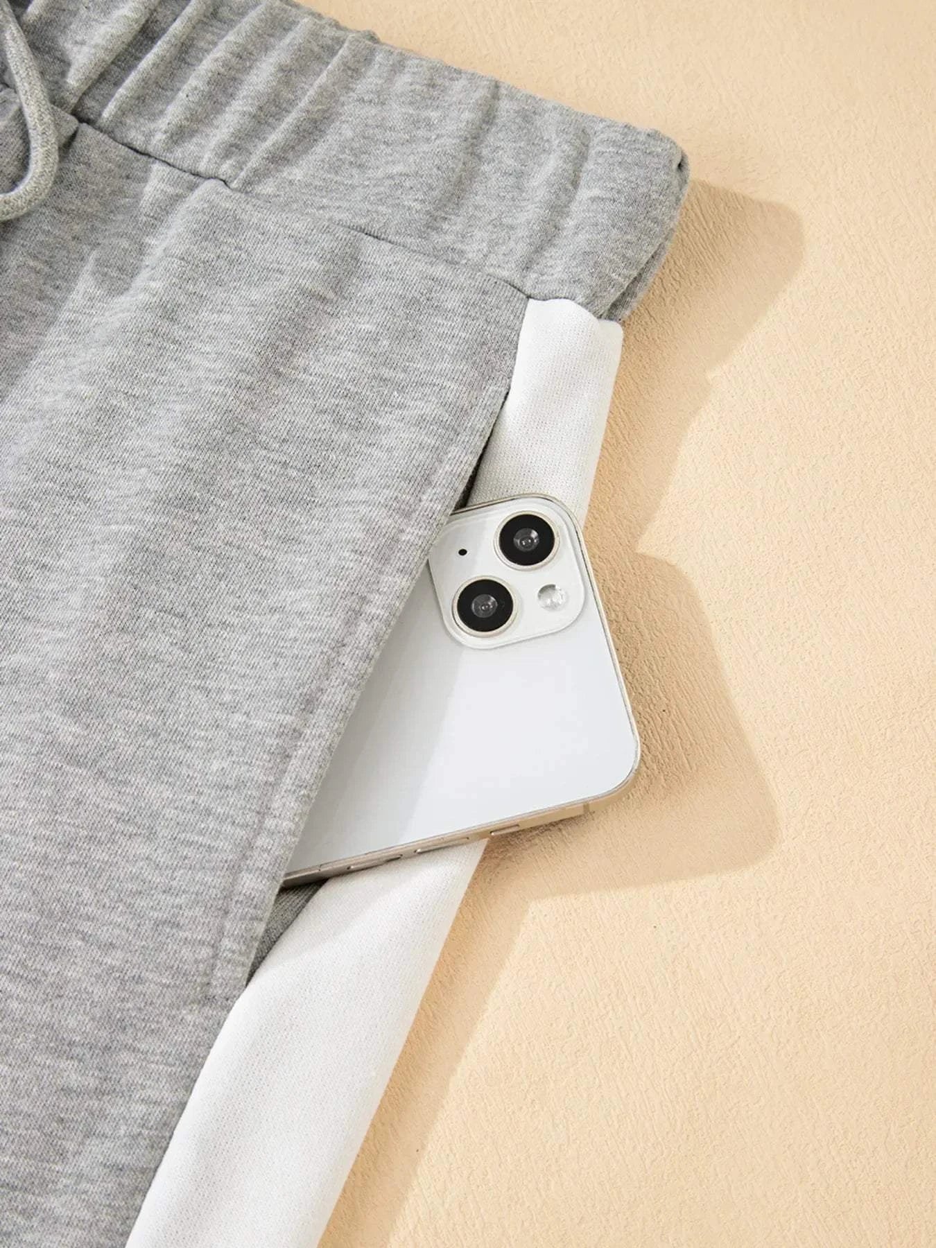 Gray pants with white contrast trim and drawstring waistband showing a phone in the pocket from the Contrast Trim Round Neck Top and Pants Set