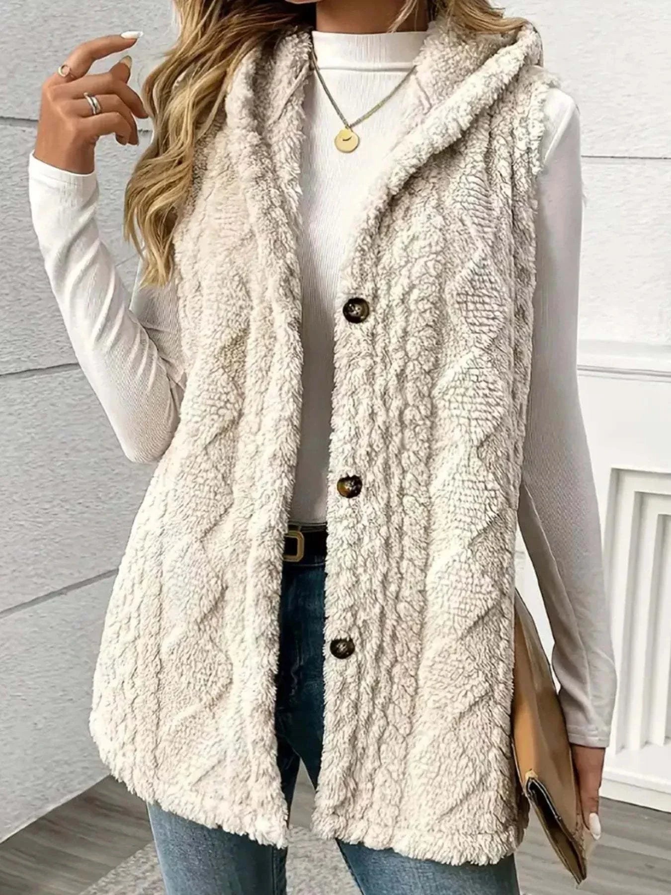 Button up plush hooded vest in cream with textured knit pattern and button closure over white long sleeve top