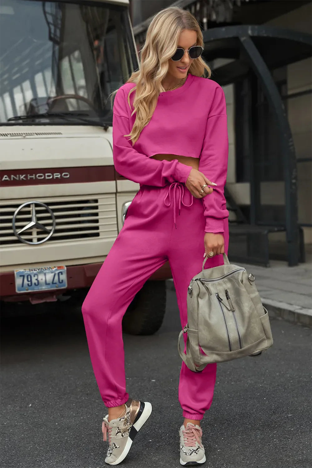 Woman wearing pink round neck long sleeve cropped top and pants set with drawstring and no stretch