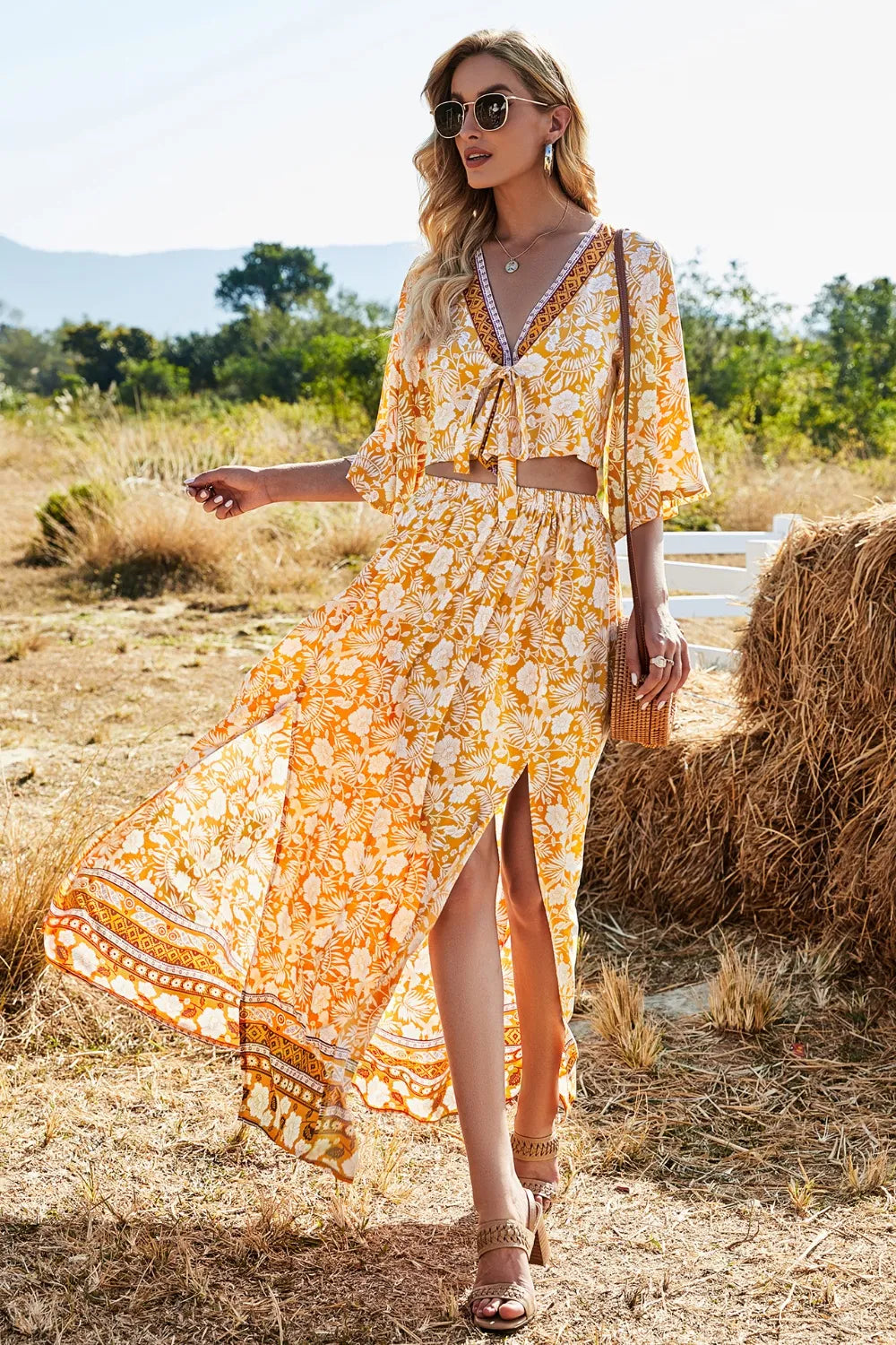 Woman wearing printed half sleeve top and slit skirt set in yellow floral pattern outdoors