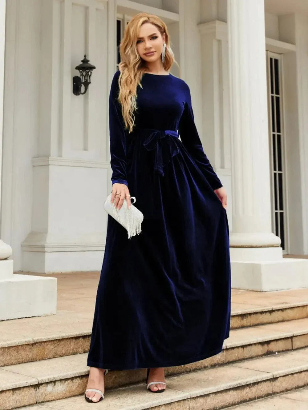 Woman wearing navy blue tie front round neck long sleeve maxi dress standing outdoors
