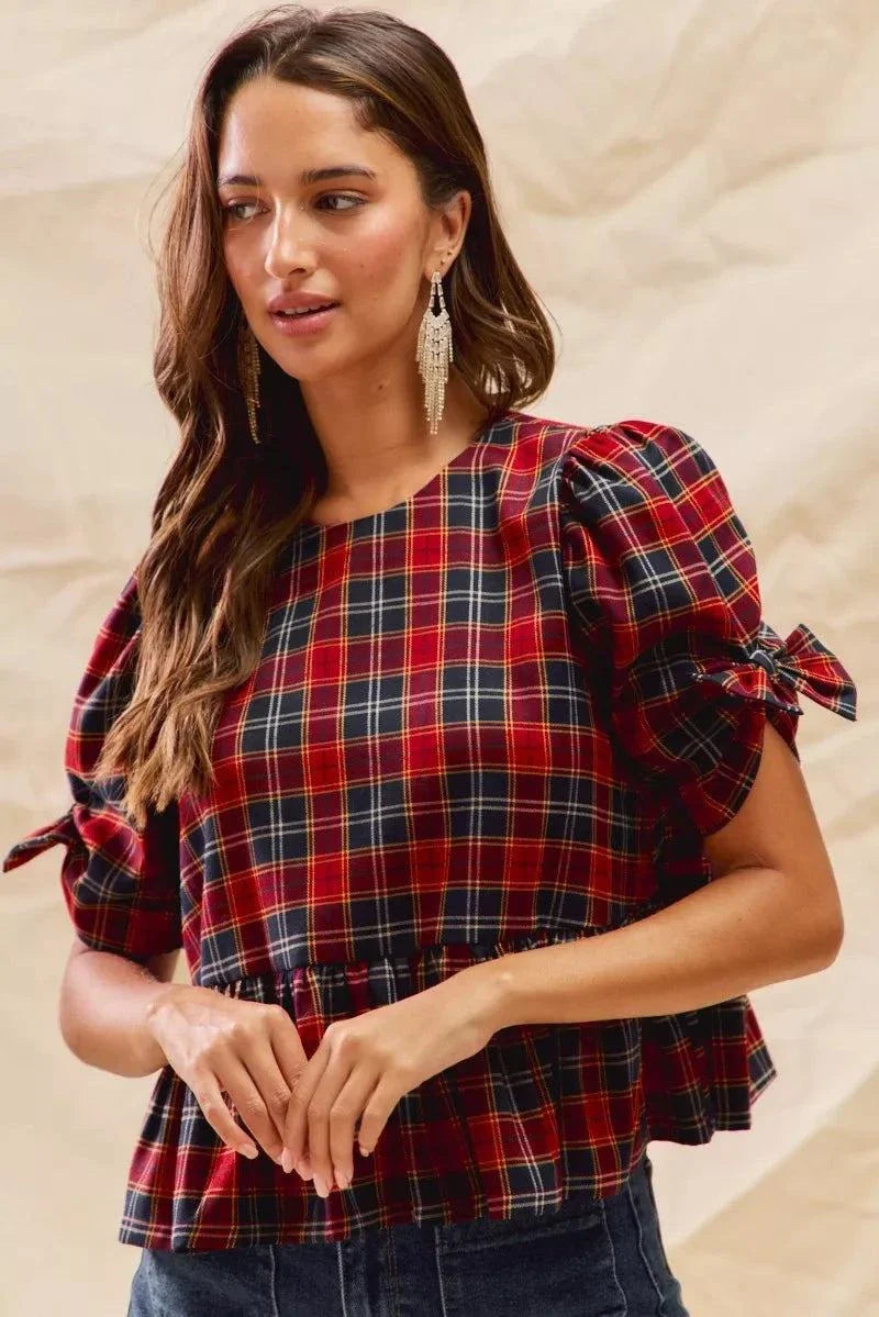Woman wearing a Christmas holiday plaid ribbon short sleeves top with ruffled details and tied sleeves