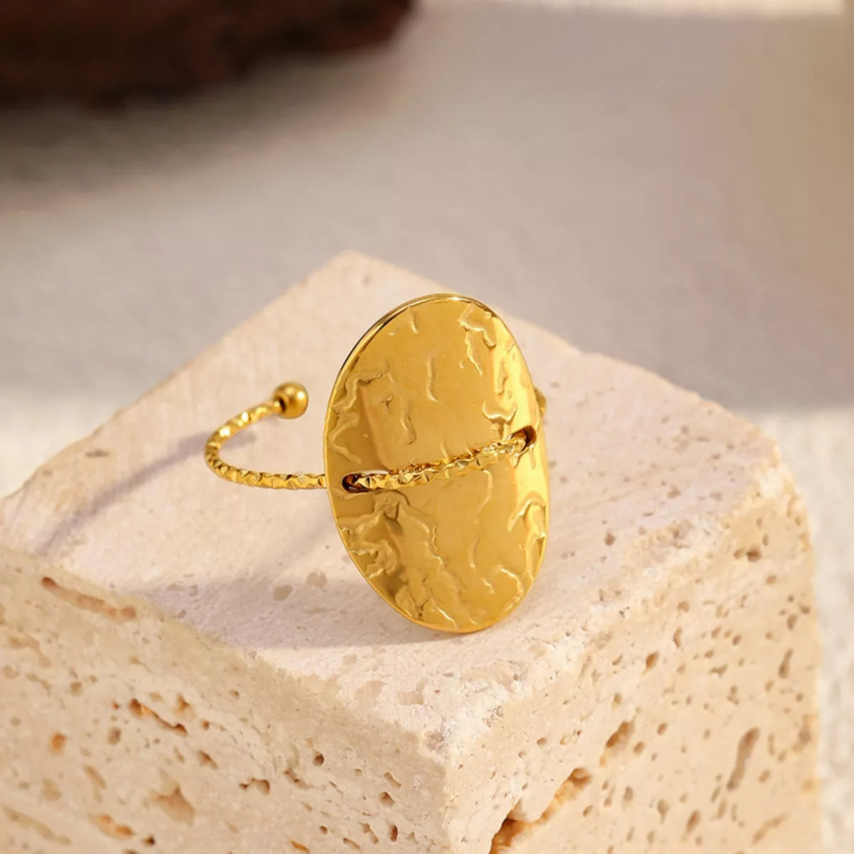 18K gold-plated hammered disc open ring with stainless steel adjustable band on textured stone block