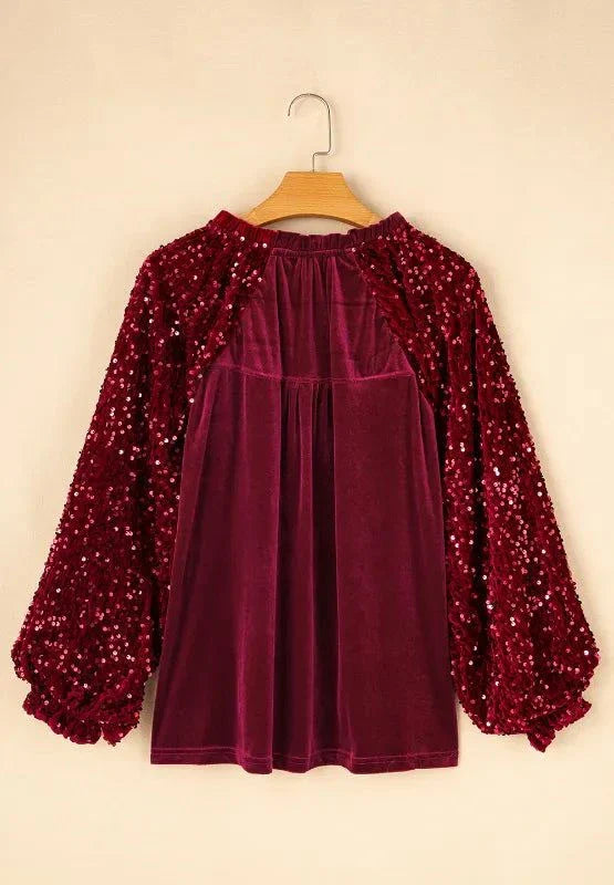 Burgundy sequin notched long sleeve blouse with slightly stretchy opaque fabric and gathered sleeves hanging on wooden hanger