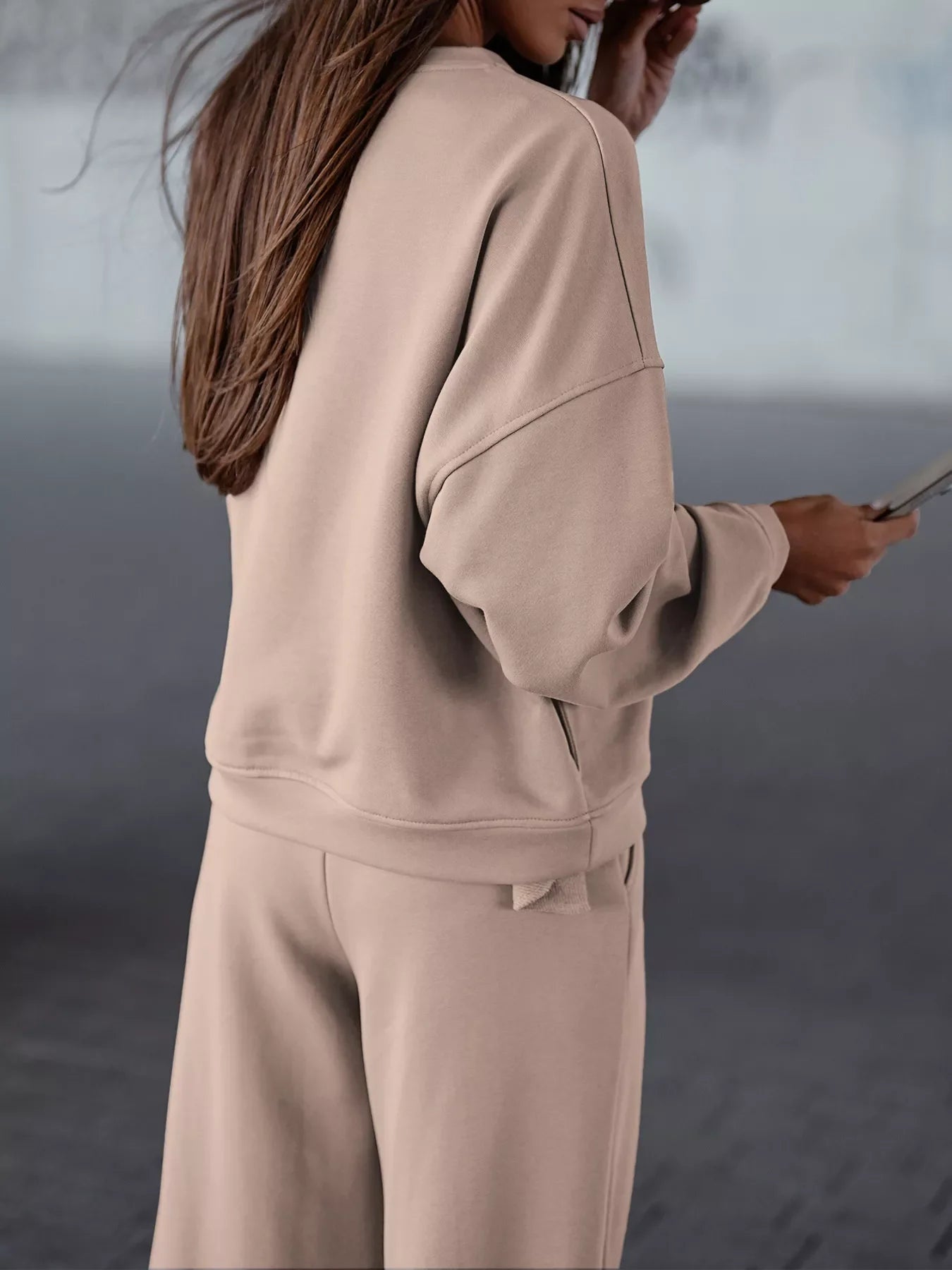 Woman wearing a beige casual loose fit top and pants two-piece set with pockets and slightly stretchy fabric