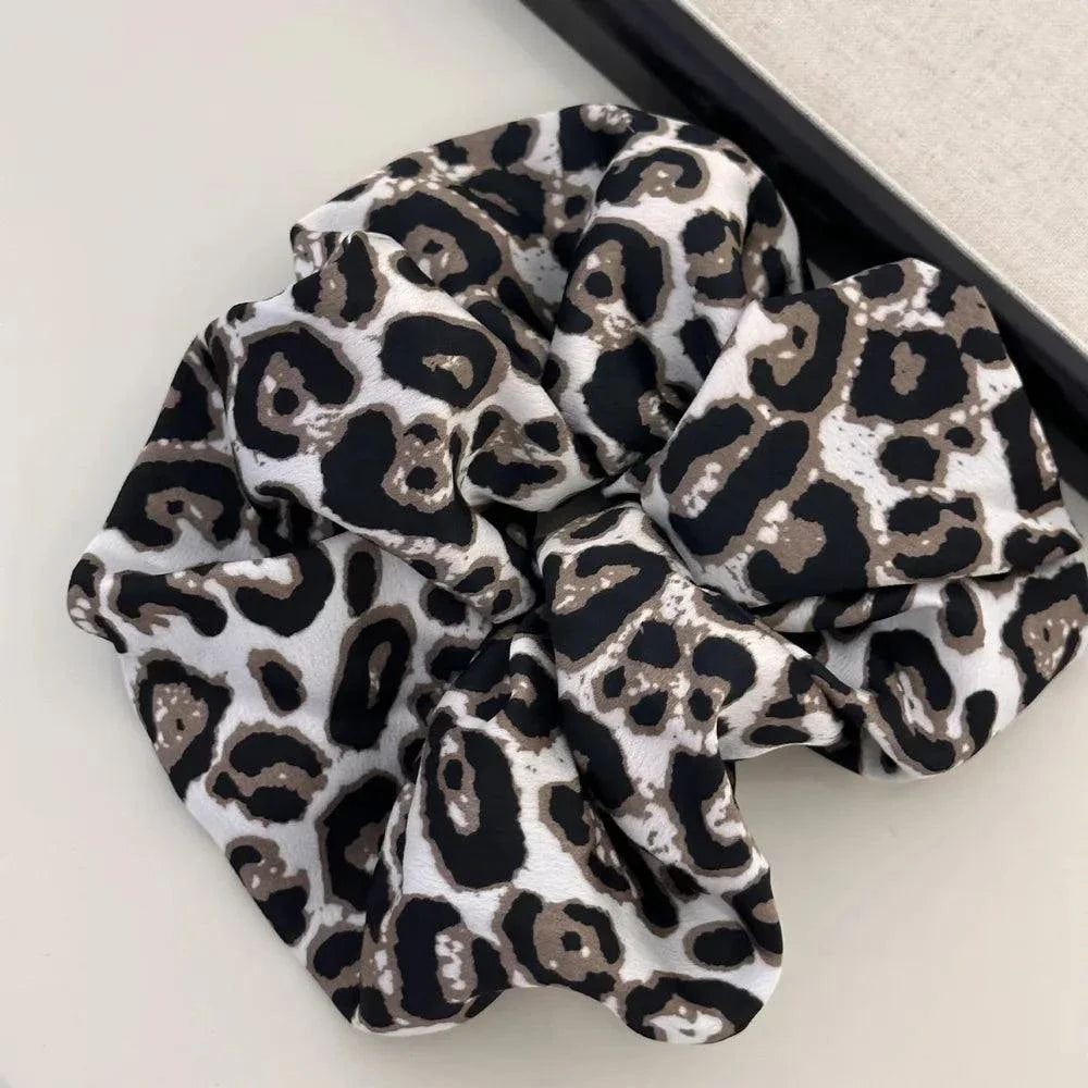 Leopard elastic hair scrunchy made of polyester with black and brown spots on a light background