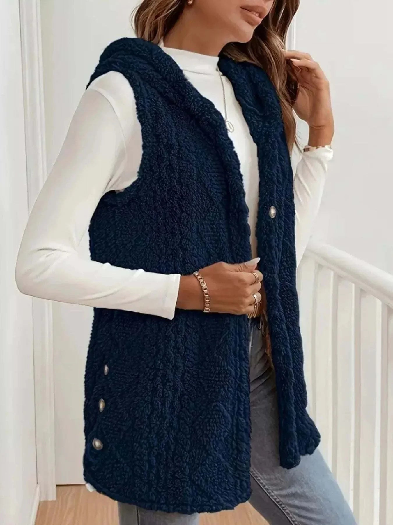 Woman wearing navy button up plush hooded vest over white long sleeve top