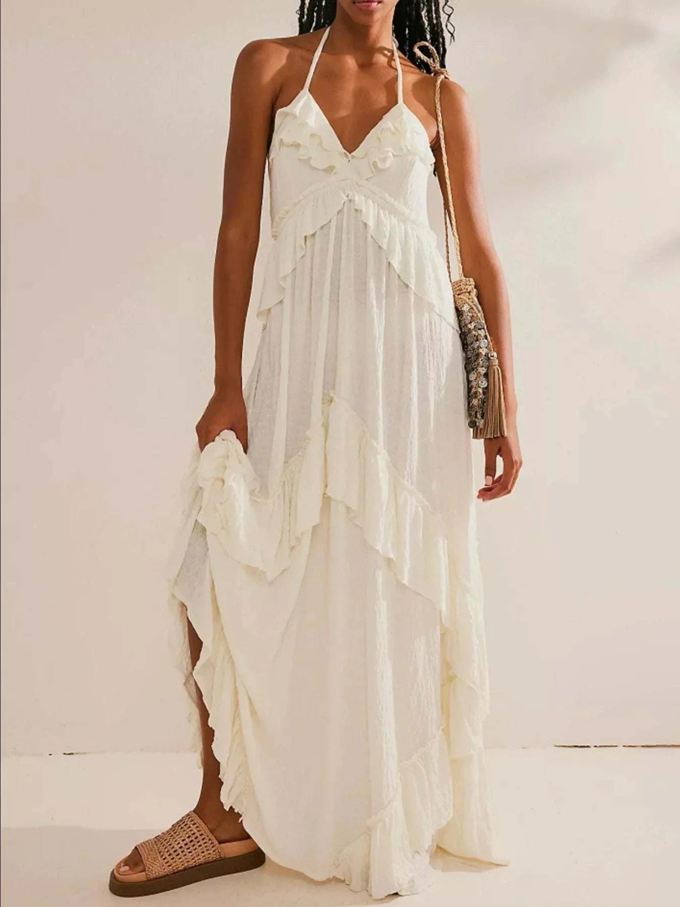 Woman wearing white ruffled halter neck maxi dress with tiered layers and tied straps