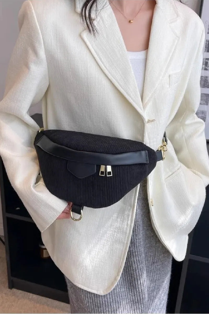 Black corduroy crossbody bag with removable strap worn with white blazer and skirt