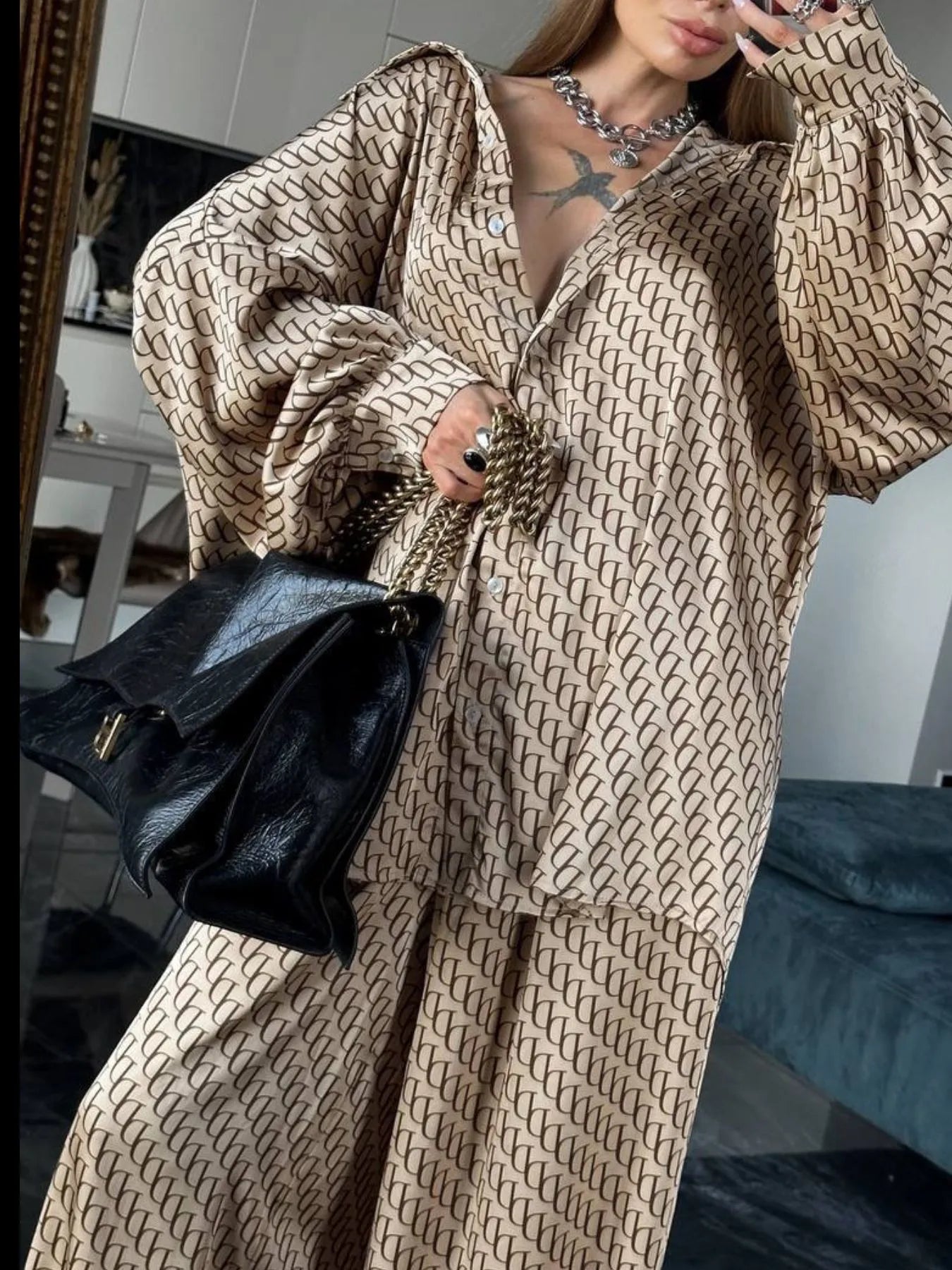 Oversized printed button up shirt and pants set in beige with black pattern, styled with black handbag and silver chain necklace