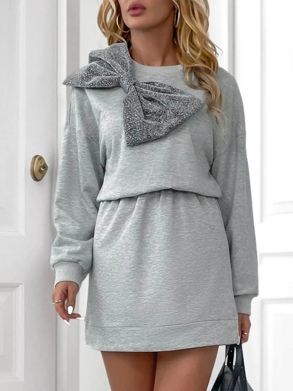 Woman wearing light grey Perfee Bow Mini Dress with dropped shoulder, long sleeves, and large bow detail on shoulder