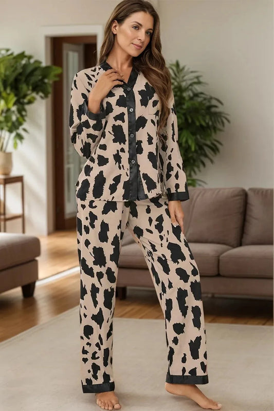 Woman wearing a beige and black button up long sleeve top and pants lounge set with abstract pattern in living room