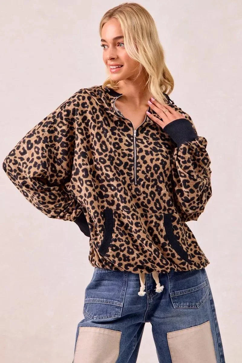 Woman wearing leopard print waffle half zip hoodie with front pockets and drawstring hem.