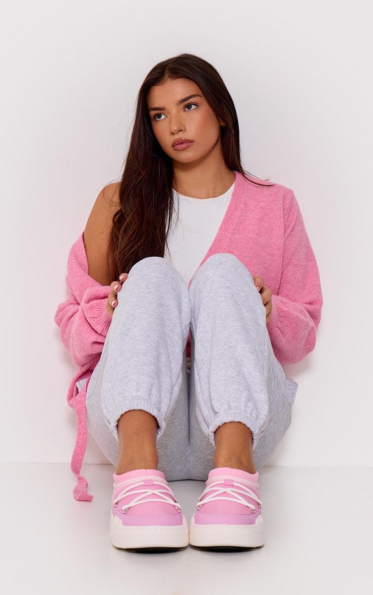 Woman wearing pink MOON BOOT Pink Park Icon slip-on sneakers sitting against white background