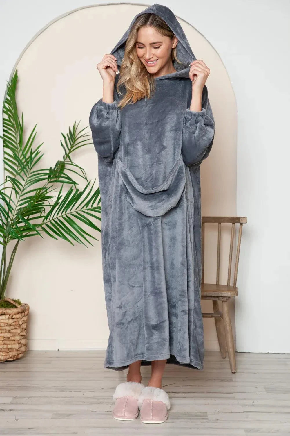 woman wearing gray hooded midi lounge dress with full-size pockets and slippers indoors