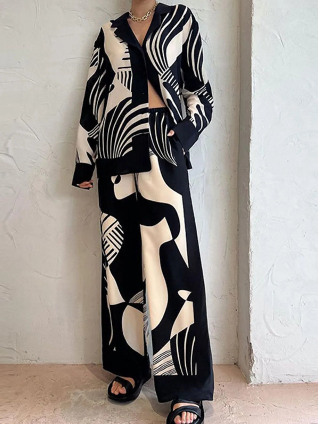 Two-piece printed long sleeve shirt and pants set with buttoned front and pockets in black and white abstract pattern