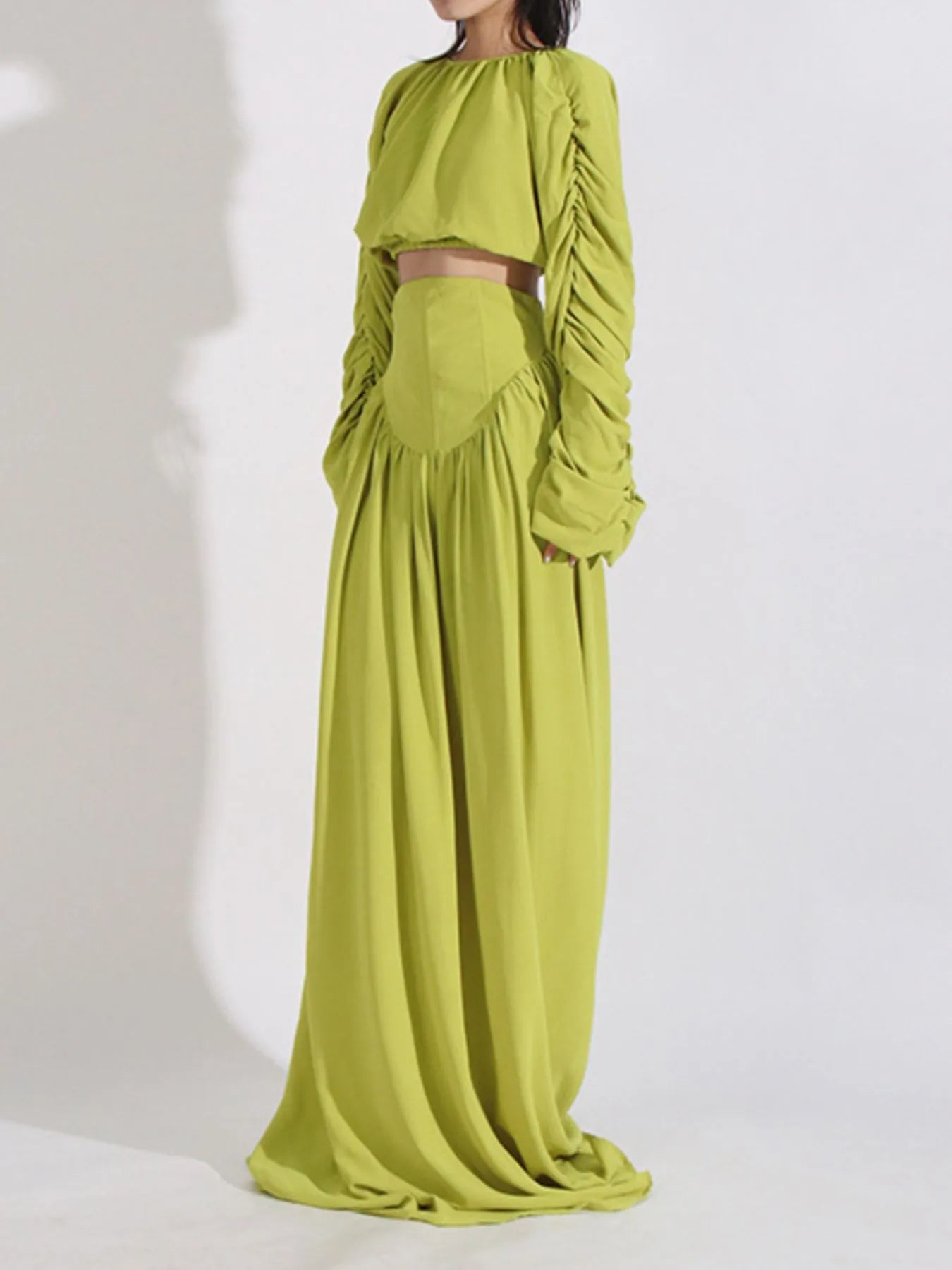 Woman wearing a lime green ruched long sleeve top and high waist skirt set made of slightly stretchy polyester