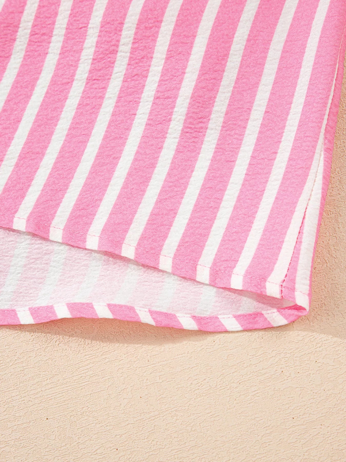 Pink and white striped fabric close-up of buttoned front sleepwear top edge
