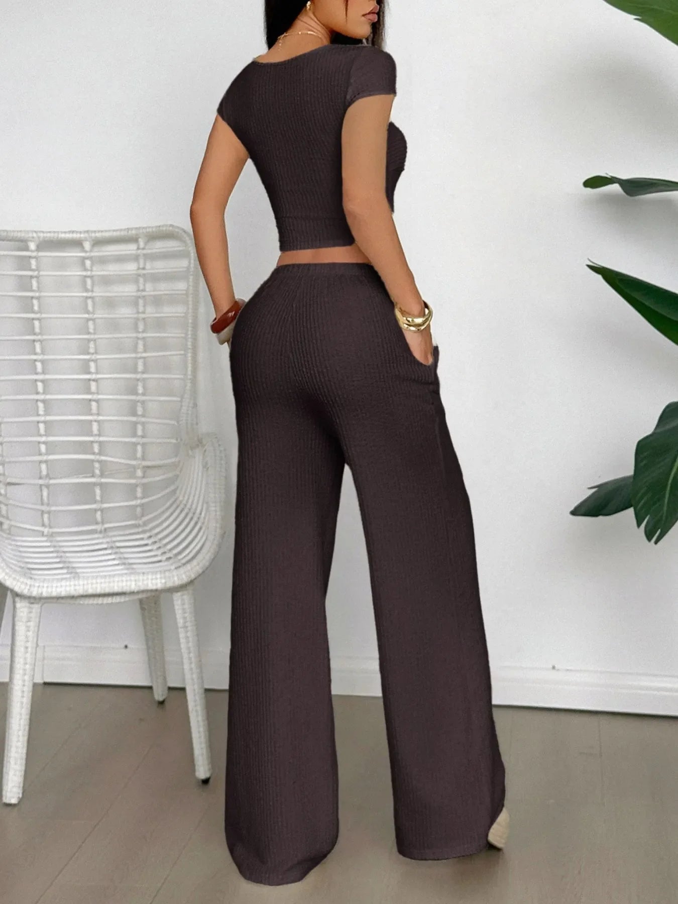 Woman wearing black cutout short sleeve top and pants set with crisscross and tied details