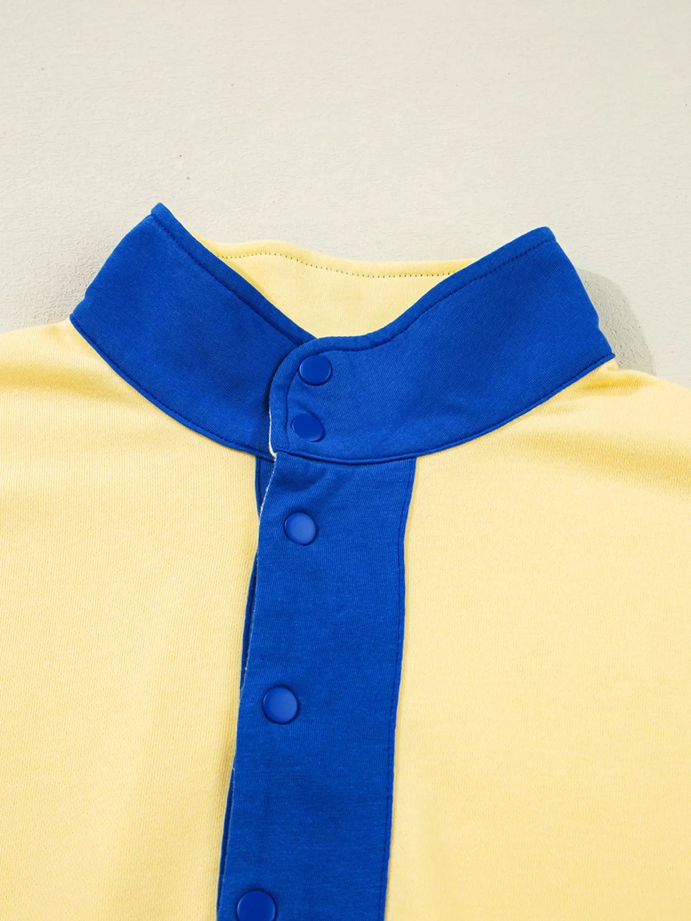 Close-up of color block patchwork half button blue collar on yellow top