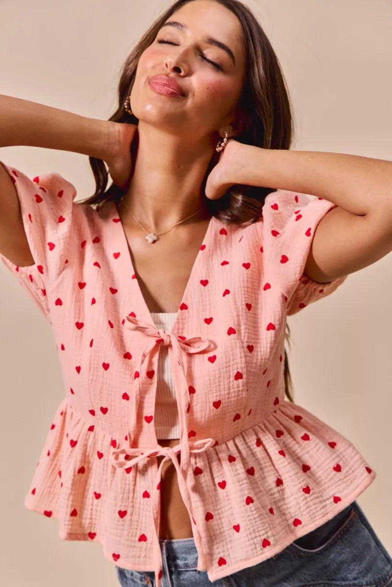 woman wearing pink all over heart ribbon tie baby doll Valentine blouse with red heart print and short sleeves