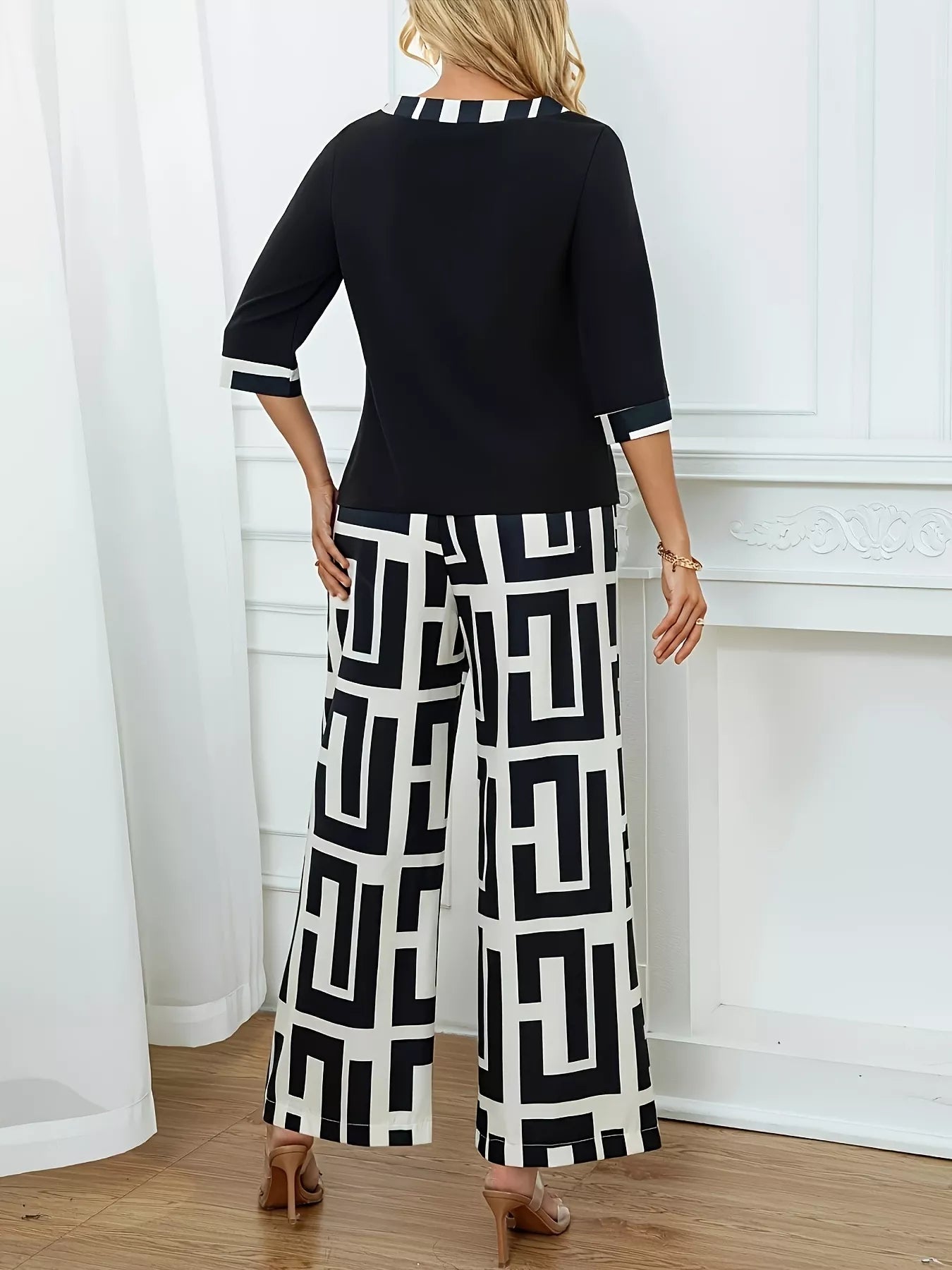 Woman wearing black geometric print round neck top and matching wide-leg pants two-piece set from back view