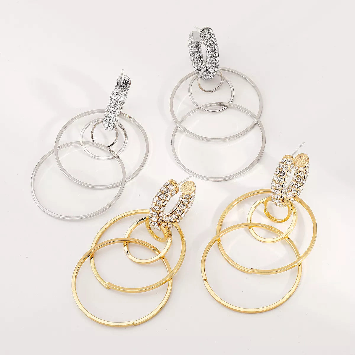 Pair of rhinestone hoop dangle earrings in gold and silver tones with multiple hoops and 18K gold plating