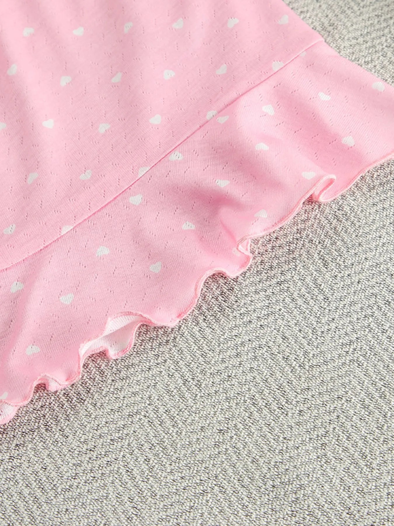 Close-up of pink polka dot round neck top with ruffled hem from lounge set