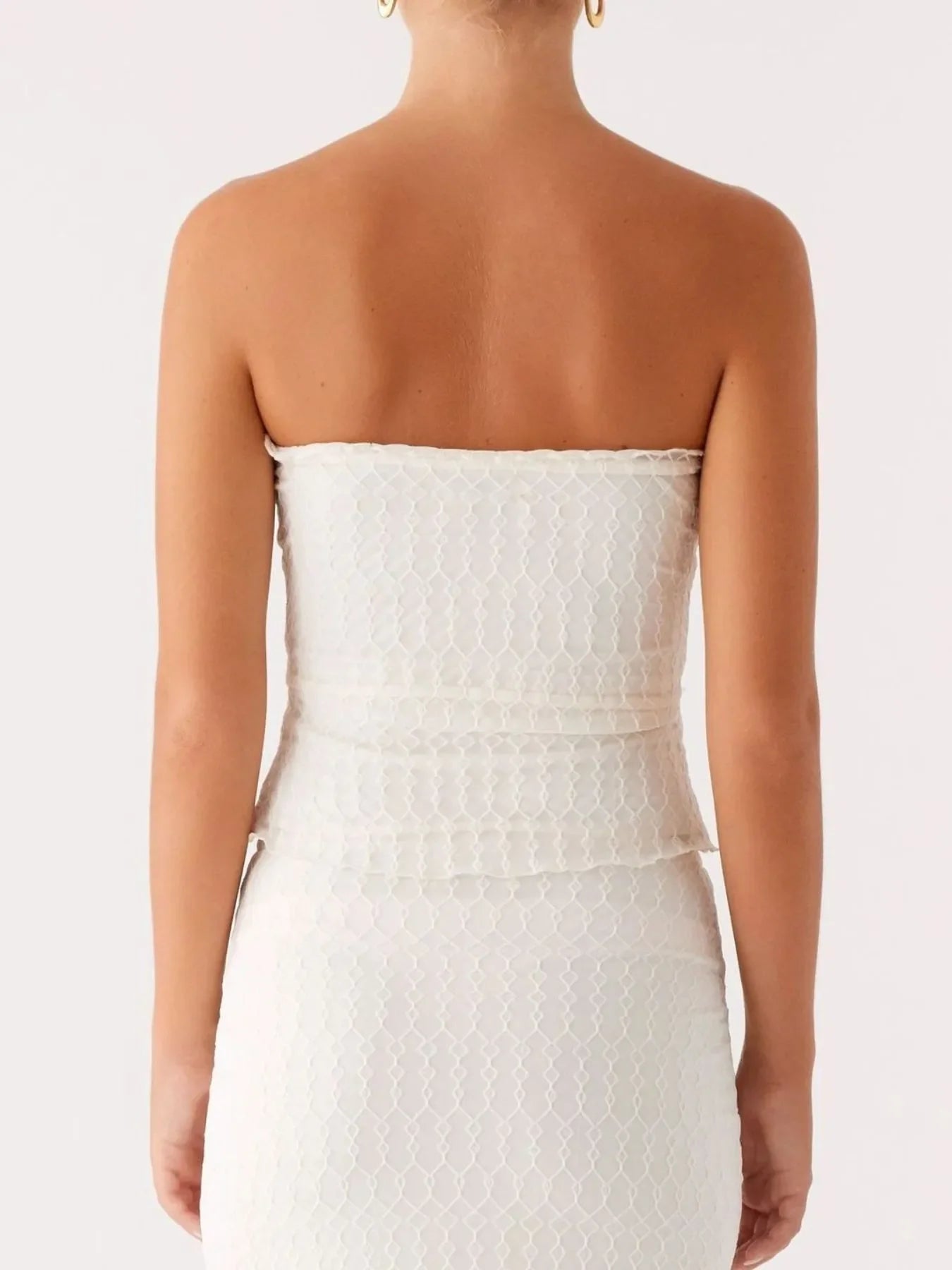 back view of woman wearing white lace tie front tube top and maxi skirt set