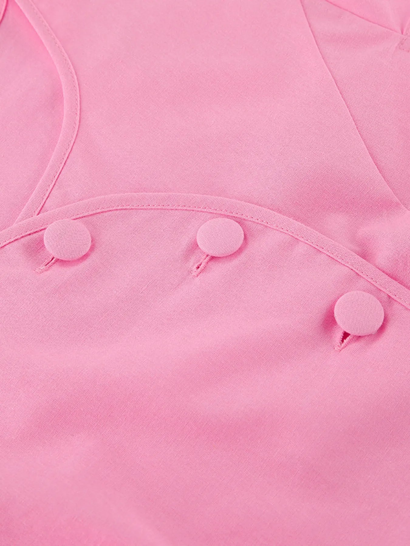 Close-up of pink short sleeve top with buttoned detail made of 100% cotton