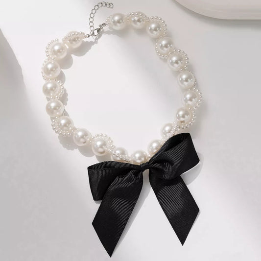 Elegant pearl choker necklace with black bow accent and adjustable chain for a stylish look