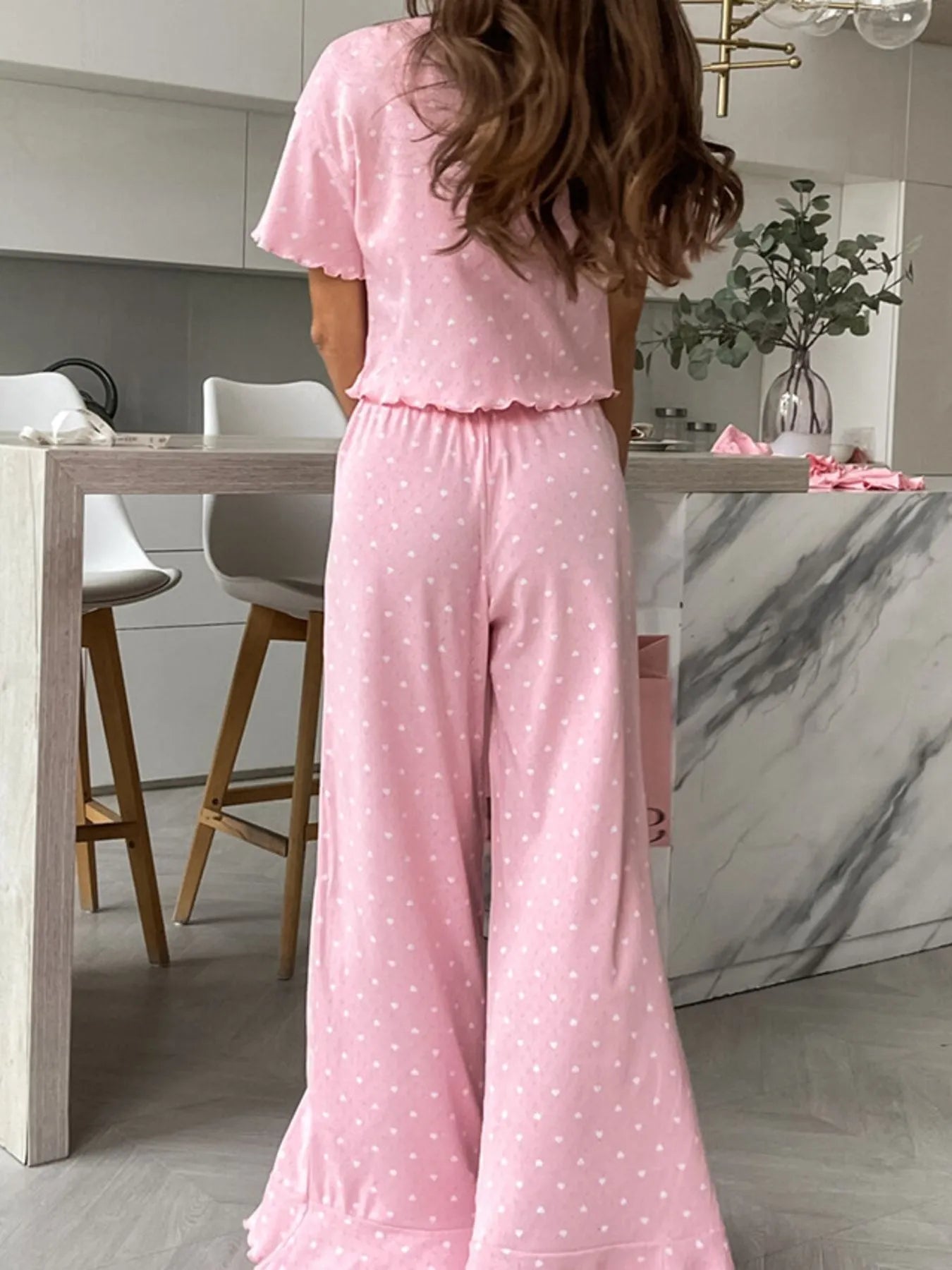 Pink polka dot round neck top and pants lounge set with ruffled edges and slight stretch, made of 100% polyester