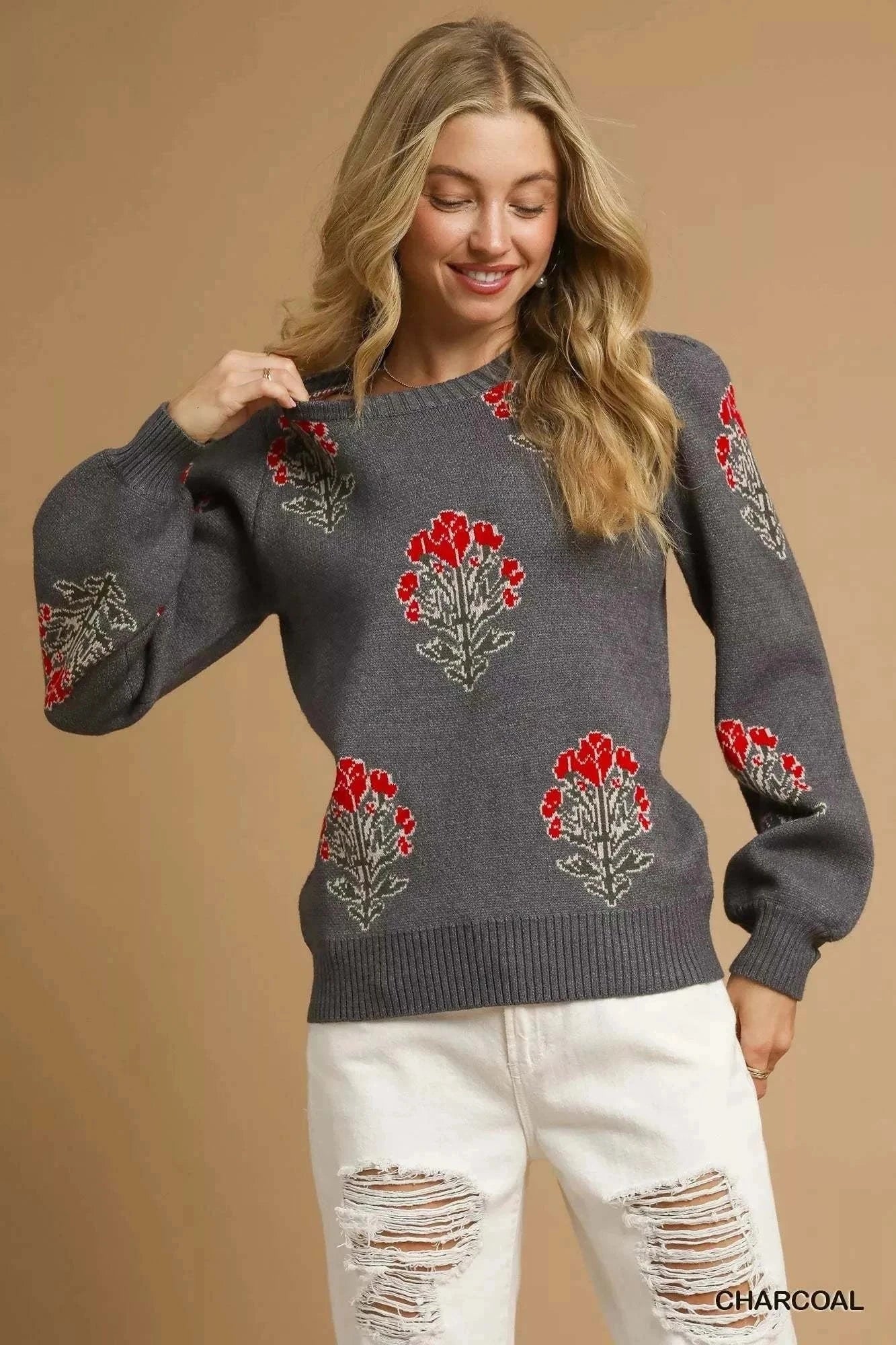 Woman wearing charcoal Umgee Flower Stem Jacquard Sweater with red floral patterns and white distressed jeans