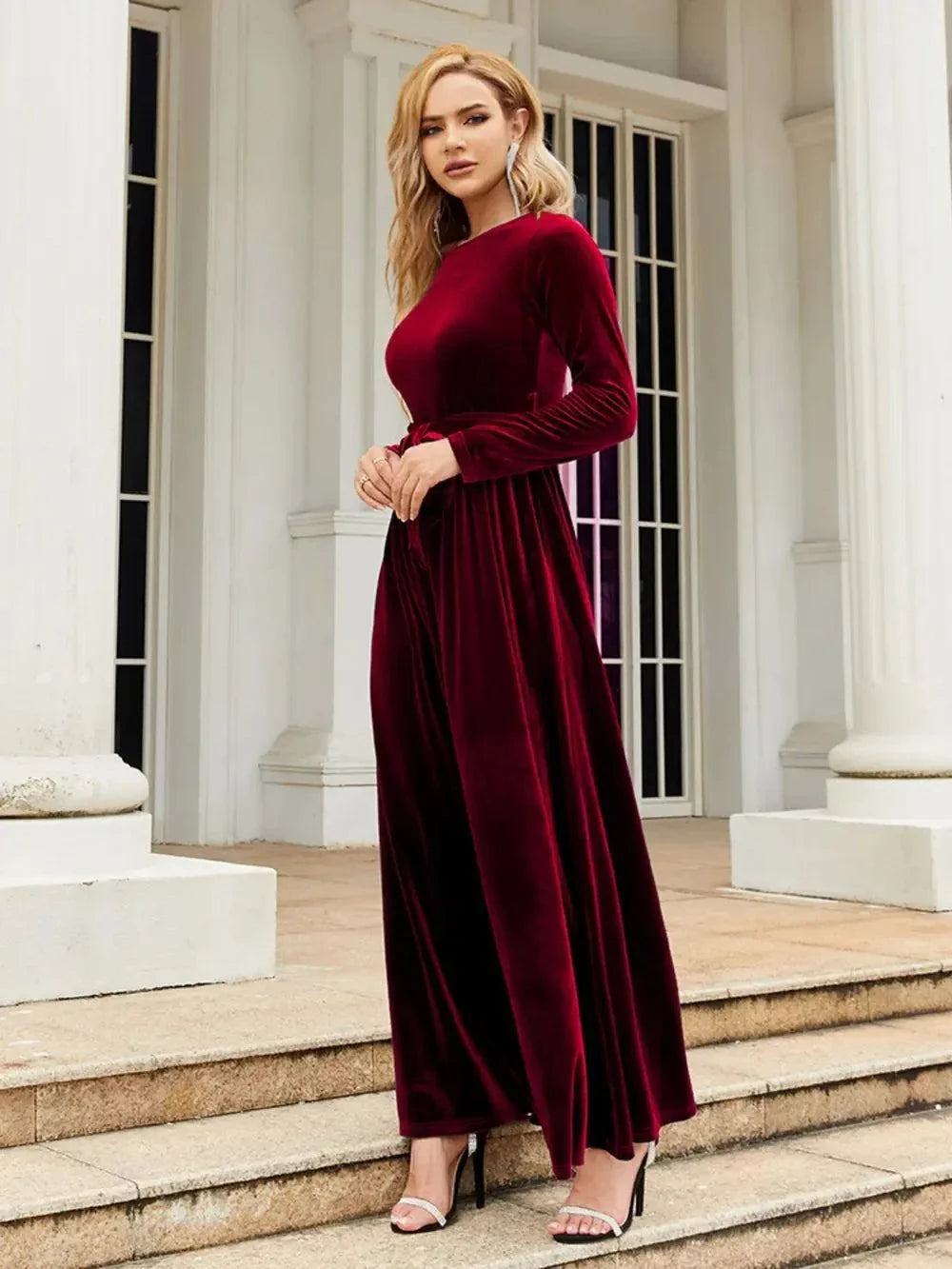Woman wearing tie front round neck long sleeve burgundy maxi dress standing on steps