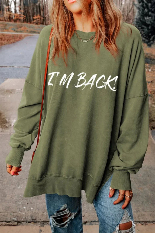 Woman wearing olive green I'M BACK dropped shoulder sweatshirt with ripped jeans outdoors
