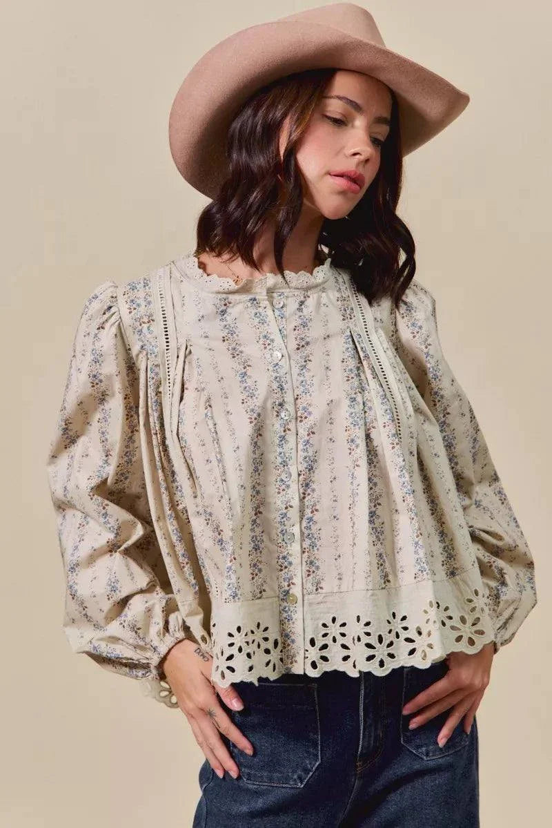 Woman wearing floral print lace button-down blouse with ruffled and eyelet details paired with hat and jeans